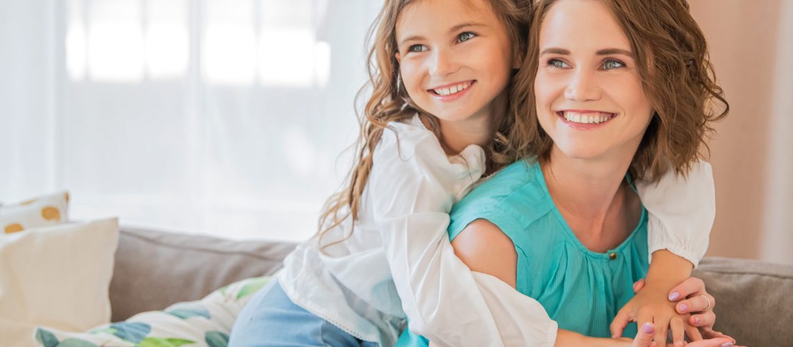 Happy mother and teenage daughter hug each other at home.